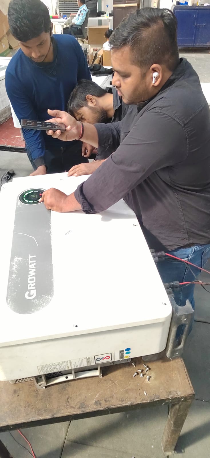Technicians testing a Growatt solar inverter during repair work