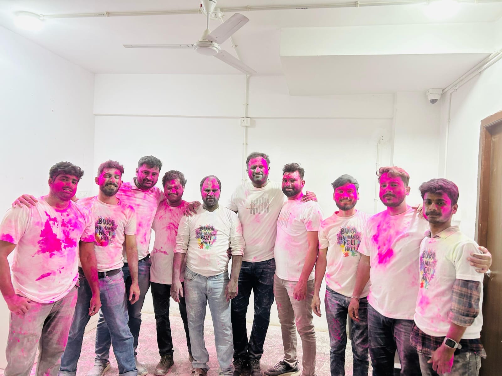 Team celebrating Holi indoors with pink colors